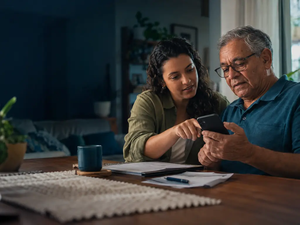 Como ver os descontos no extrato do INSS: aposentado confere o extrato do benefício no celular com a ajuda da filha